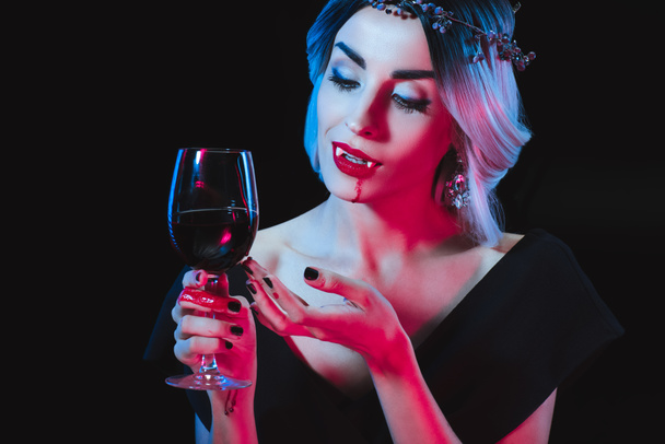 sexy vampire woman holding wineglass with blood isolated on black - Photo, Image