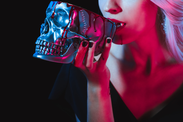 vista recortada de vampiro bebiendo sangre de cráneo de metal aislado en negro
 - Foto, Imagen