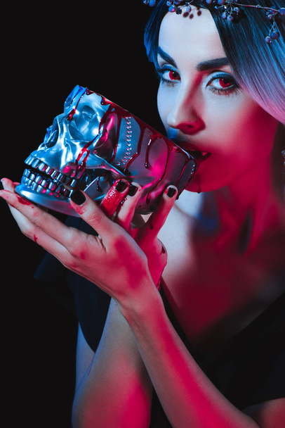 vampire drinking blood from metal skull isolated on black - Photo, Image