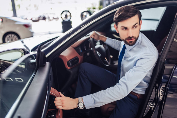 portrait of pensive businessman looking away while sitting in car - Fotó, kép
