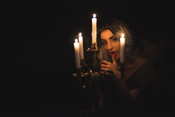 vampire licking her fingers isolated on black - Fotoğraf, Görsel