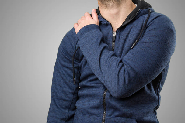 junger Mann mit Rückenschmerzen auf grauem Hintergrund - Foto, Bild