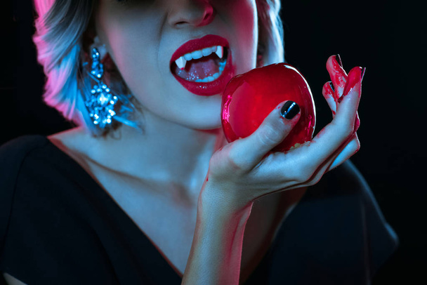 обрезанный вид вампира кусающего кровавое красное яблоко, изолированное на черном
 - Фото, изображение