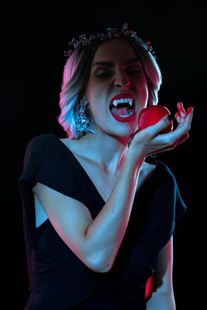 вампир кусает кровавое яблоко, изолированное на черном
 - Фото, изображение