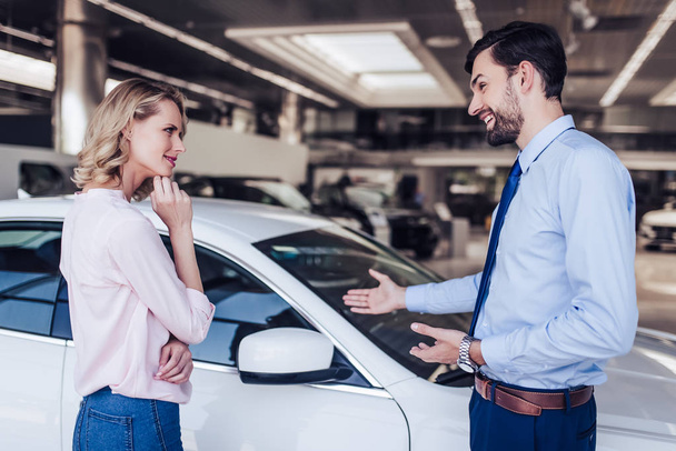 female client and salesman looking at new car in dealership salon - Foto, immagini