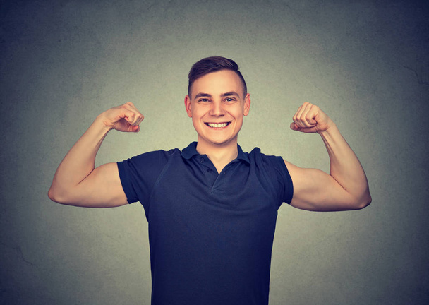Happy fit young man showing biceps and smiling at camera excited with success - Foto, immagini