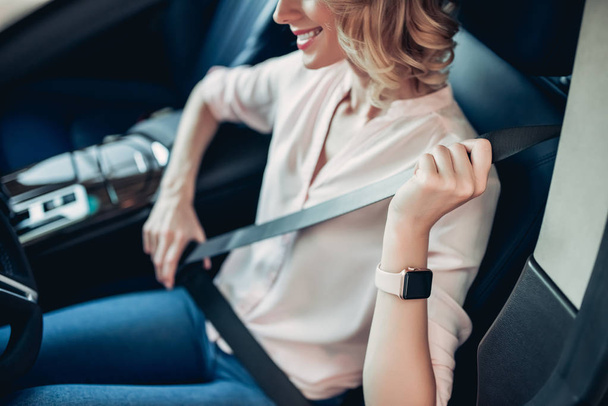 cropped shot of smiling woman fastening safety belt in the car - 写真・画像