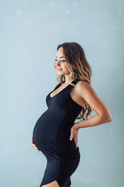 Portrait of a beautiful pregnant woman in dress in studio  - Photo, Image