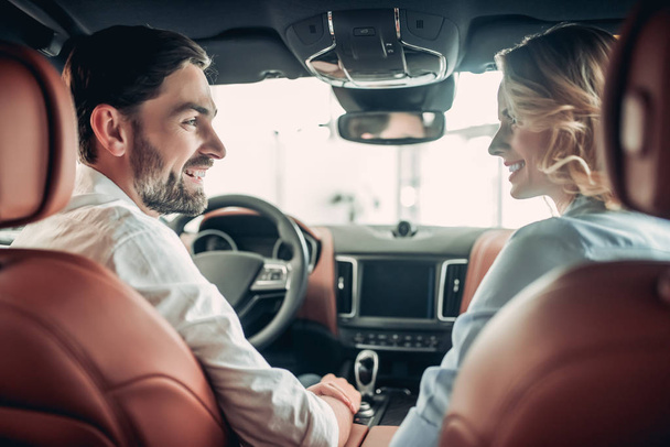 back view of of happy couple talking together while sitting in new car - Foto, Imagem
