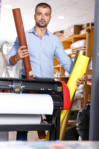 працівник чоловічої друкарні з рулонами кольорового паперу
 - Фото, зображення