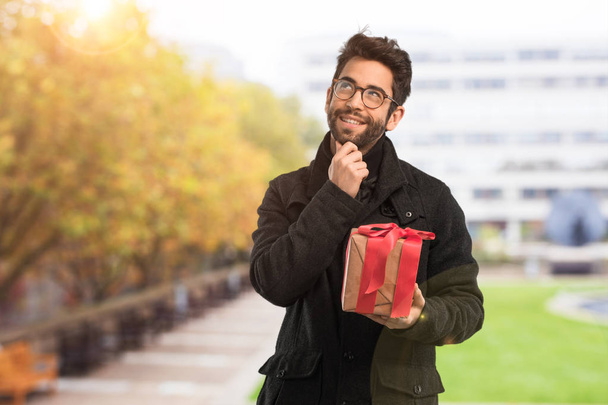 young man holding a present - Фото, зображення