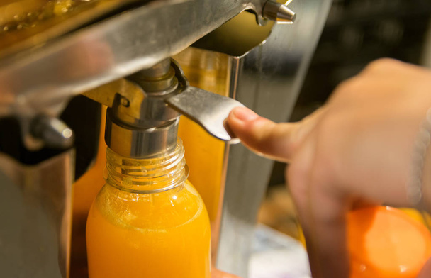 Verter jugo de naranja fresco de un dispensador
 - Foto, imagen