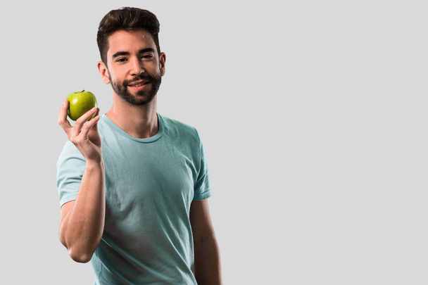 athletic young man holding an apple - Fotoğraf, Görsel