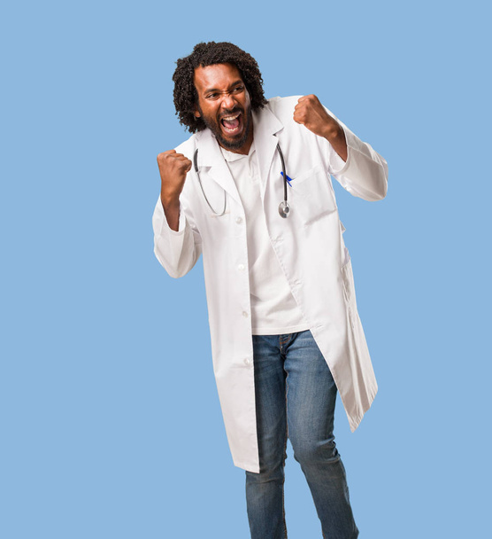 Pohledný americký lékař velmi šťastný a nadšený, zvyšování paže, slaví vítězství a úspěch, výhra v loterii - Fotografie, Obrázek