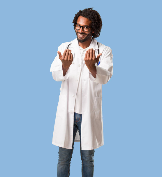 Handsome african american medical doctor inviting to come, confident and smiling making a gesture with hand, being positive and friendly - Fotografie, Obrázek