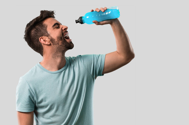 içme ve bir şişe tutan atletik genç adam - Fotoğraf, Görsel