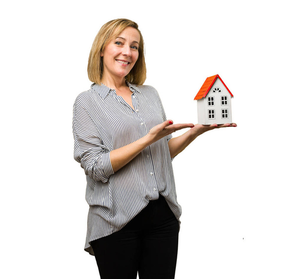 блондинка зріла жінка тримає міні будинок
 - Фото, зображення
