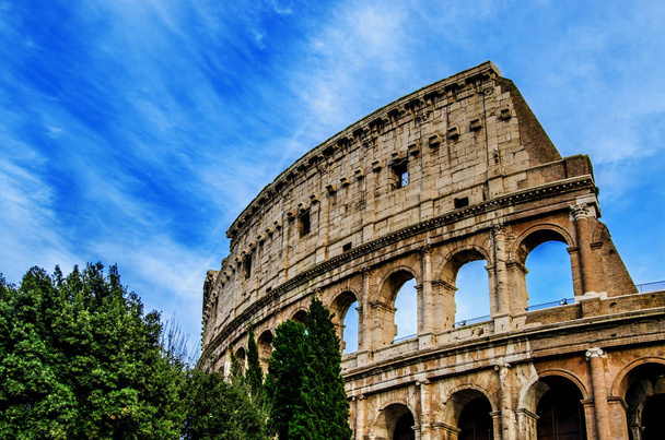 Los antiguos arcos del Coliseo contra el cielo azul con rastros blancos de las nubes flotantes. En Roma. Italia
 - Foto, imagen