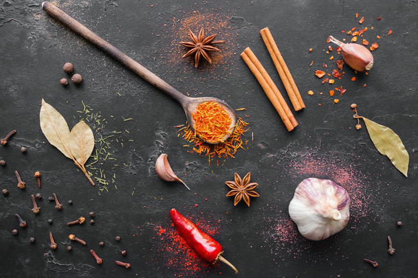 spices, seasonings in spoons and herbs on a black background - Fotografie, Obrázek