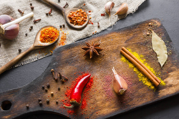 Spices and herbs for cooking on a cutting board and in wooden spoons - Foto, immagini