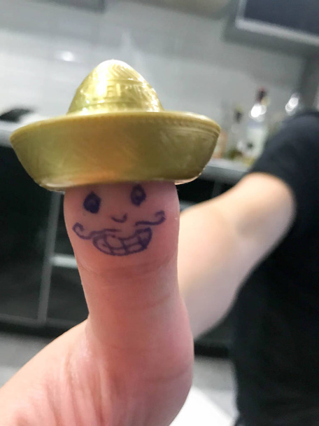 Polegar, dedo mexicano em sombrero chapéu de ouro com rosto alegre pintado com bigodes e olhos
 - Foto, Imagem