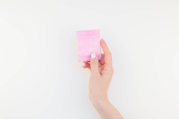 Nainen käsi pastelli manikyyri kiillottaa tilalla vaaleanpunainen päivittäin terveysside eristetty valkoisella pohjalla kopiotilaa. Malli naisellinen kauneus blogi sosiaalinen media. Naisten terveydenhuollon käsite
 - Valokuva, kuva