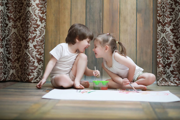 Niños pequeños pintan en una hoja grande de papel
 - Foto, Imagen