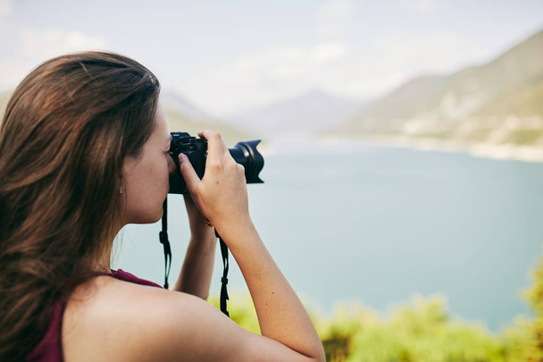 Young tourist Girl taking pictures of mountains and lake. Georgia. Summer. August. - 写真・画像