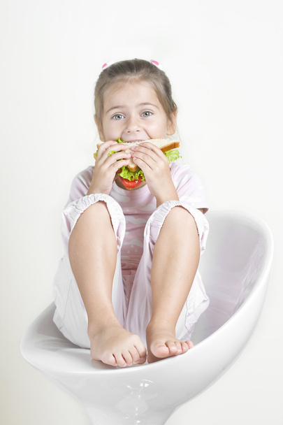 Досить маленька дівчинка їсть бутерброд
 - Фото, зображення