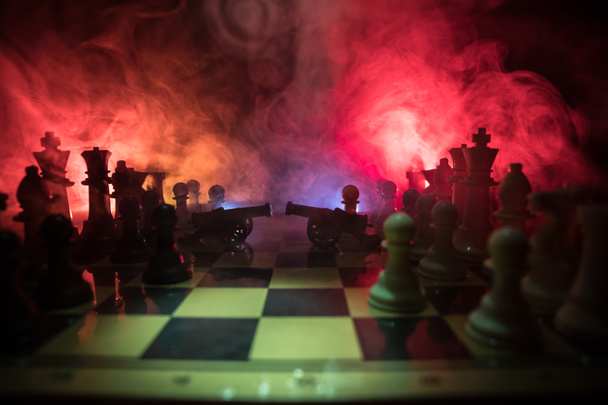 Středověká bitva scéna s dvěma dělo na šachovnici. Koncept desková hra šachy podnikatelských nápadů a myšlenek konkurence a strategii šachové figurky na tmavém pozadí se kouře a mlhy. - Fotografie, Obrázek