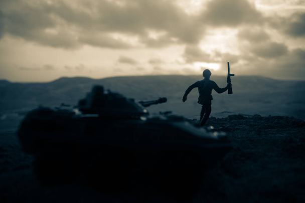 Έννοια του πολέμου. Στρατιωτική σιλουέτες καταπολέμηση σκηνή στην ομίχλη πολέμου φόντο του ουρανού, παγκόσμιο πόλεμο στρατιώτες σιλουέτες κάτω νεφελώδη ορίζοντα στο ηλιοβασίλεμα. Στρατιώτης που προσπαθούν να ξεφύγουν από την δεξαμενή - Φωτογραφία, εικόνα