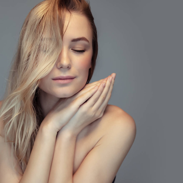 Authentic beauty and natural cosmetics concept, closeup portrait of a beautiful blond woman with closed eyes isolated on gray background, photo with copy space - 写真・画像