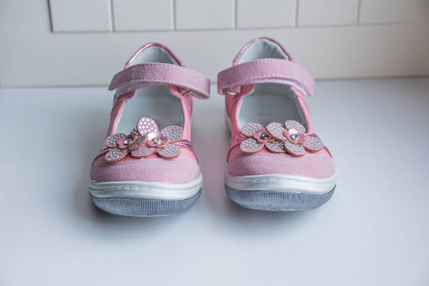 Paar schattige baby sandalen versierd met bloemen op witte achtergrond, kopie ruimte. Meisjes fashion.baby roze lederen schoenen geïsoleerd op wit. Kleine meisje kleding collectie. - Foto, afbeelding