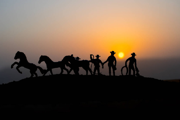Cowboy concept. Silhouette of Cowboy at sunset time. Cowboys silhouettes on a hill with horses. Selective focus - Photo, Image
