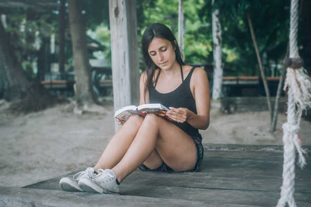Mujer joven acostada en columpio en la playa tropical, leyendo libros. Koh Tao, Tailandia
 - Foto, imagen