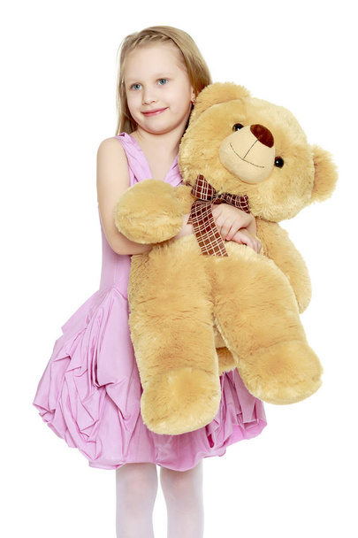 Beautiful little girl 5-6 years.She is holding a large teddy bea - Foto, Imagen