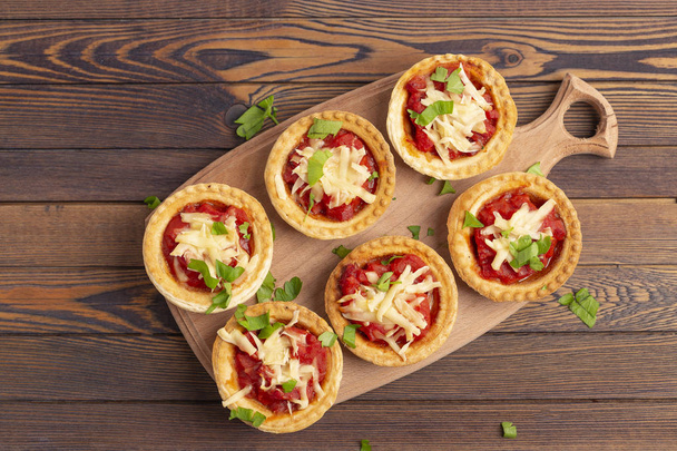 Mini pizza with salami, tomato and cheese on wooden background. Tasty appetizer, tartlet.  - Foto, immagini