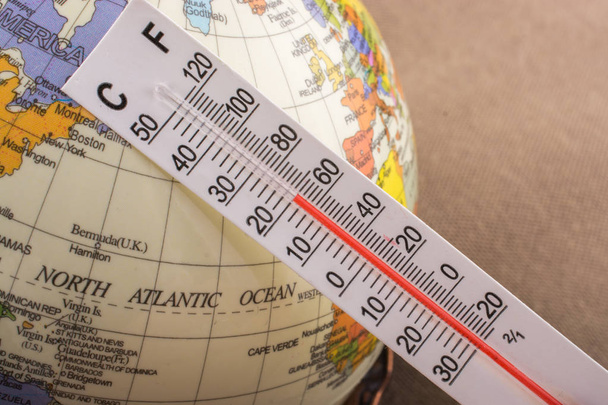 Ręka wprowadzania termometr na mały Globus modelu - Zdjęcie, obraz