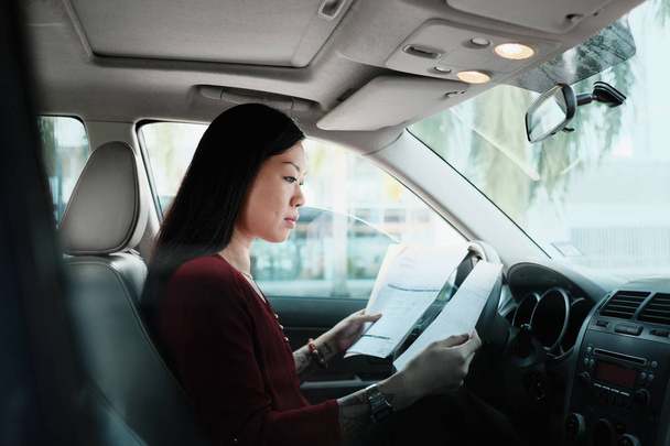 Femme d'affaires chinoise occupée travaillant dans la voiture avec des papiers
 - Photo, image