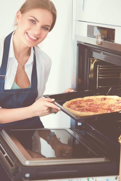 Happy young woman cooking pizza at home - Фото, зображення