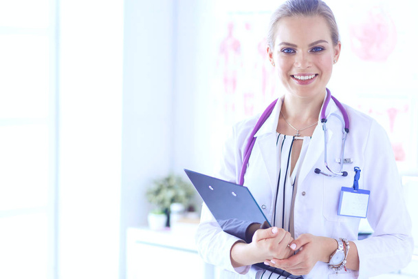 Χαμογελαστή γυναίκα γιατρός με ένα φάκελο σε όρθια θέση - Φωτογραφία, εικόνα