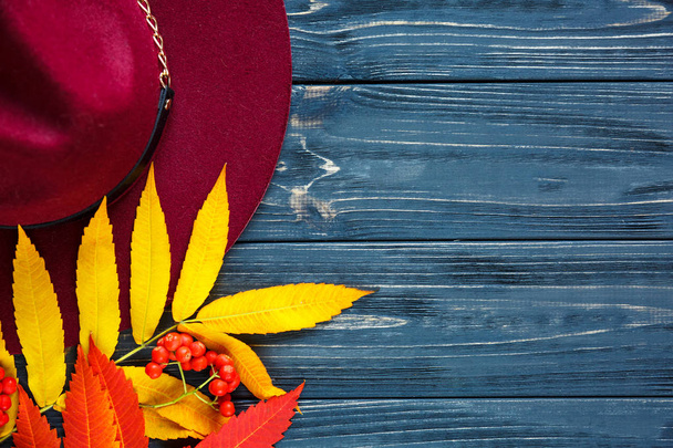 Chapeau de couleur Bourgogne ou marsala sur fond bois gris avec feuilles et baies jaune automne, rouges. Pose plate, copyspace
 - Photo, image