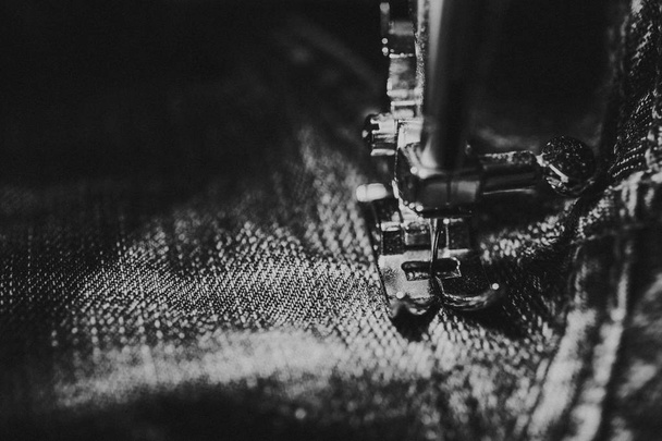 Réparer les jeans sur la machine à coudre. Vue du tissu, de l'aiguille et du fil. Éclairage de la lampe à incandescence intégrée. Les jeans sont un type de pantalon, généralement en denim ou en tissu de dungaree.
 - Photo, image