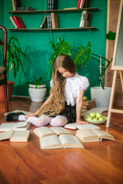 Une douce écolière de classes juniors aux longs cheveux blonds avec des livres, une commission scolaire et des pommes. Mode scolaire
 - Photo, image