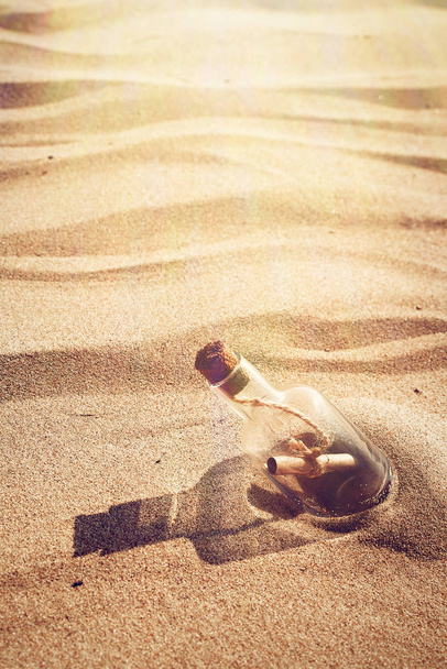 Une bouteille avec un message est lancée par une vague sur une plage de sable fin. Fond sableux. Une journée chaude ensoleillée
 - Photo, image