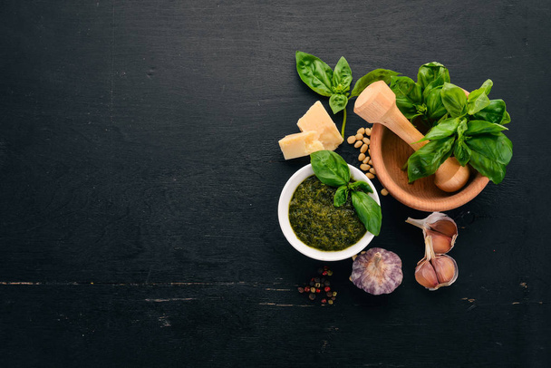Preparing basil pesto sauce. Basil, parmesan cheese, olive oil. Top view. On a black wooden background. Free space for text. - Foto, imagen