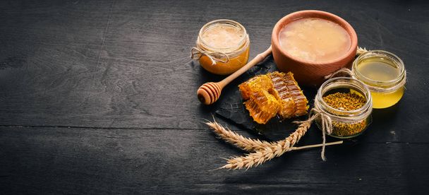 A set of honey and bee products. Honey in honeycomb. On a black wooden background. Free space for text. Top view. - Photo, Image