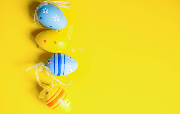 Spring Easter card with colored eggs on bright yellow background with copy space - Foto, imagen