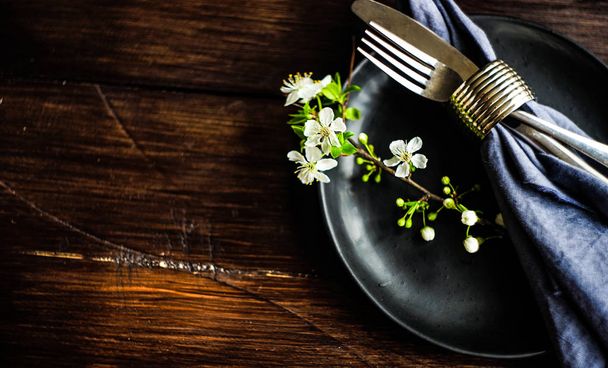 Concetto floreale primaverile con rami di ciliegio in fiore e servizio con stoviglie rustiche su tavolo in legno scuro
 - Foto, immagini