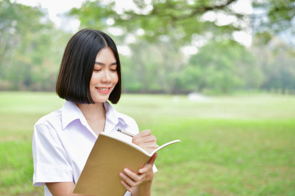 Education Concepts. Beautiful student reading books in the park. Beautiful girl are relaxing in the park. Young student are happy to read. Young student love to study. Education of Asian Women. - Photo, Image
